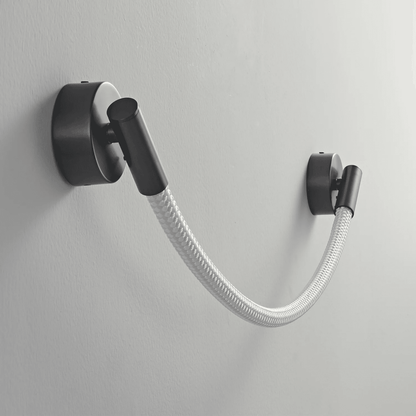 Black wall-mounted lamp with a flexible white hose on a gray background