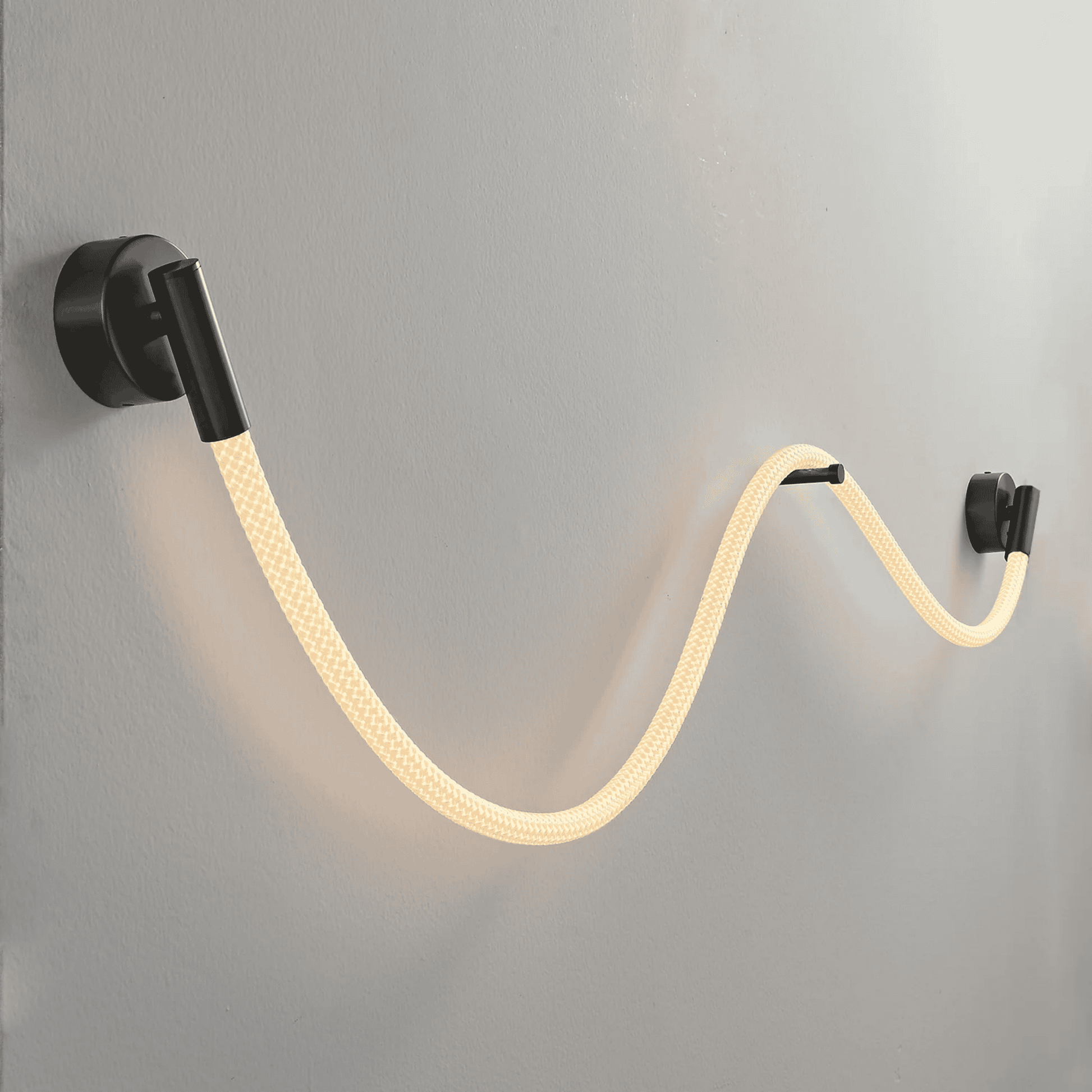 Wall-mounted light fixture with a flexible, illuminated cable on a gray wall.