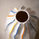 Close-up of a ceramic vase with colorful stripes on a neutral background