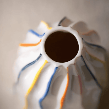 Close-up of a ceramic vase with colorful stripes on a neutral background