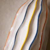 Close-up of a ceramic plate with wavy design and colorful stripes on a neutral background