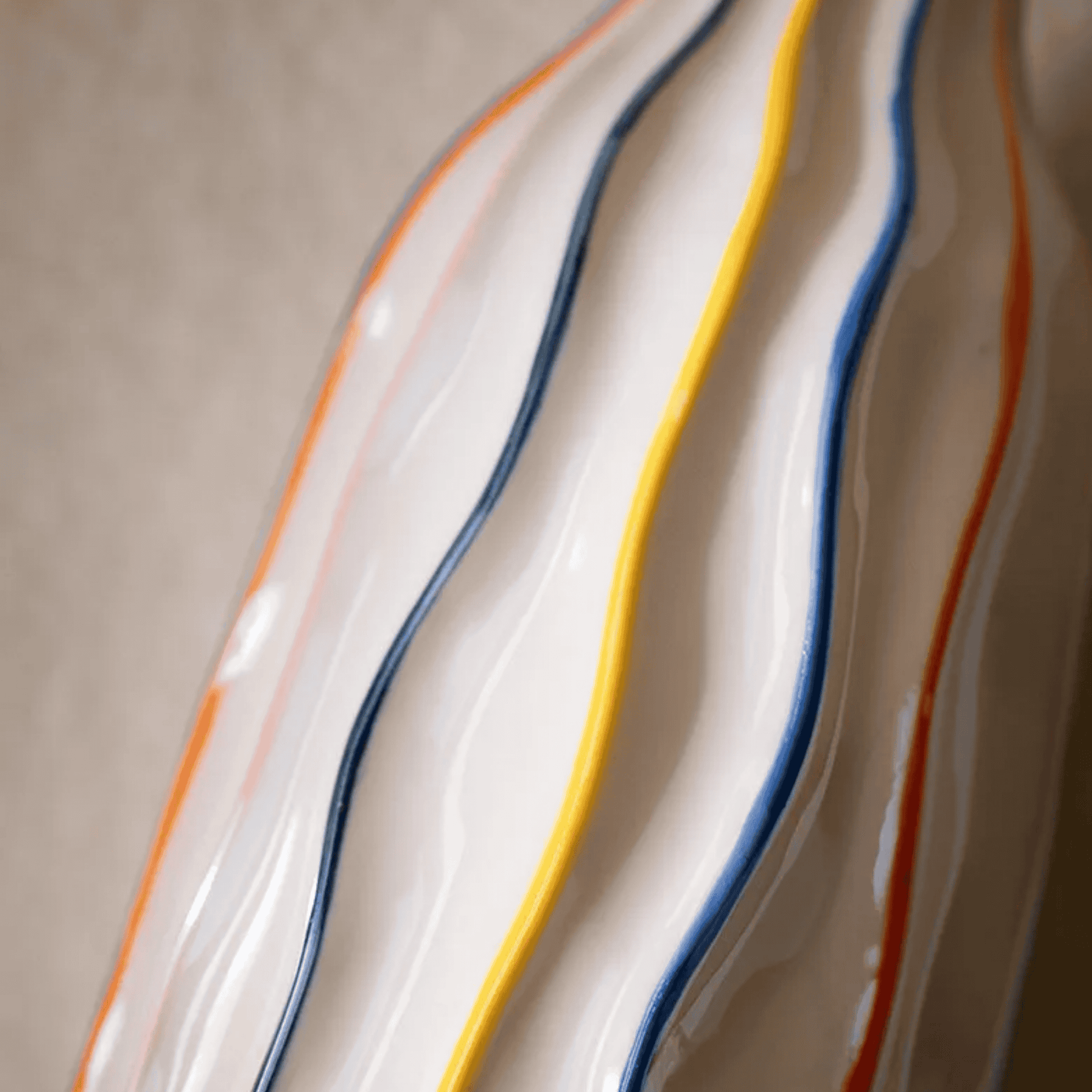 Close-up of a ceramic plate with wavy design and colorful stripes on a neutral background