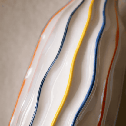 Close-up of a ceramic plate with wavy design and colorful stripes on a neutral background