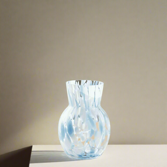 Decorative glass vase on a table with a light-colored sofa in the background