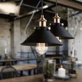 Two black pendant lights with gold accents hanging in a blurred indoor setting.