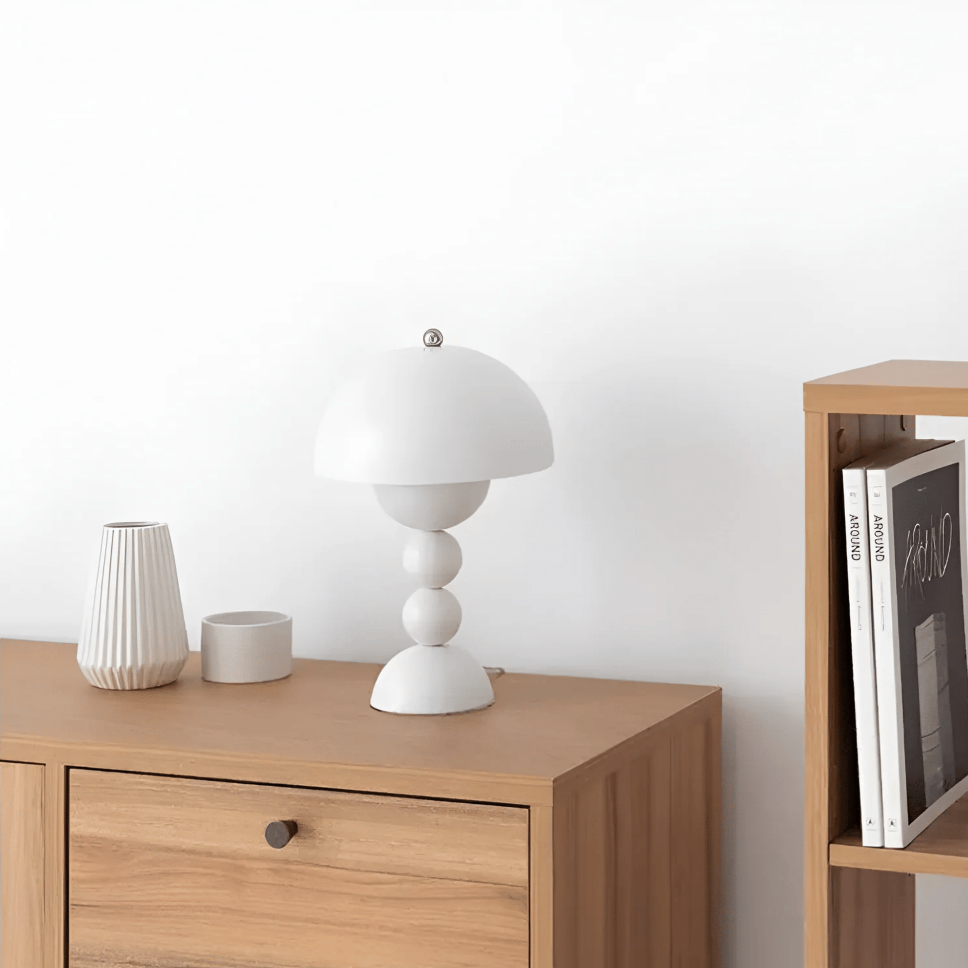 Wooden sideboard with a white lamp and decorative items against a white wall.