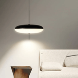 Modern pendant light hanging above a bed in a bedroom setting