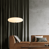Modern living room with a brown sofa, pendant light, and dark curtains.