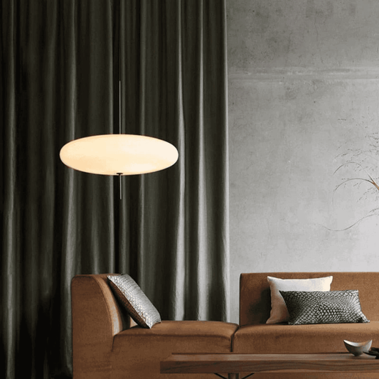 Modern living room with a brown sofa, pendant light, and dark curtains.