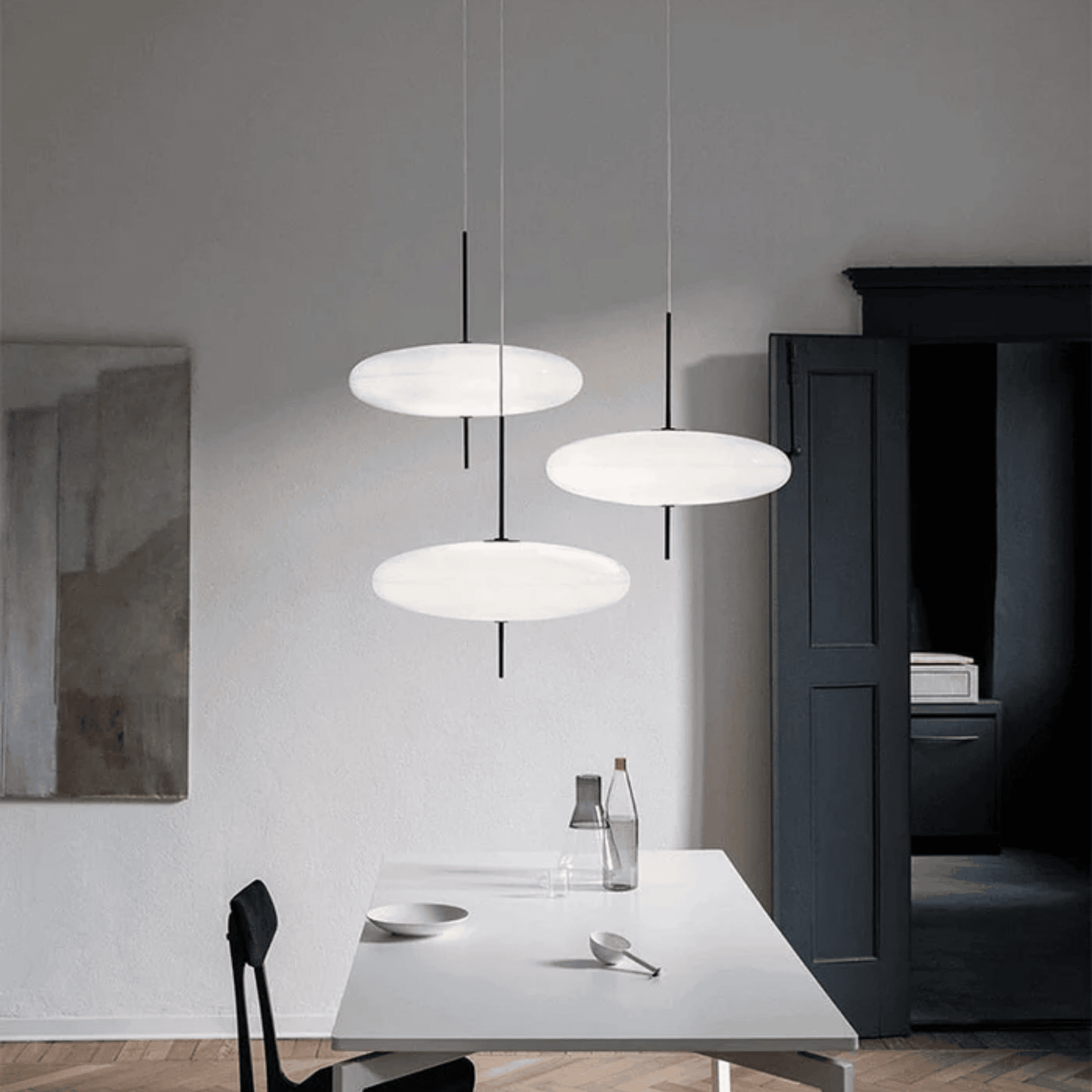 Modern pendant lights hanging above a dining table in a minimalistic room.