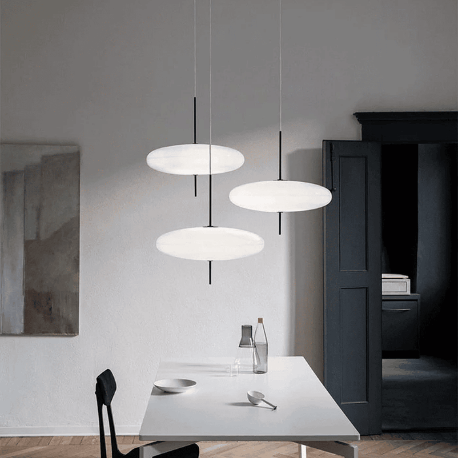 Modern pendant lights hanging above a dining table in a minimalistic room.