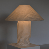 Table lamp with a beige paper bag base against a gray background