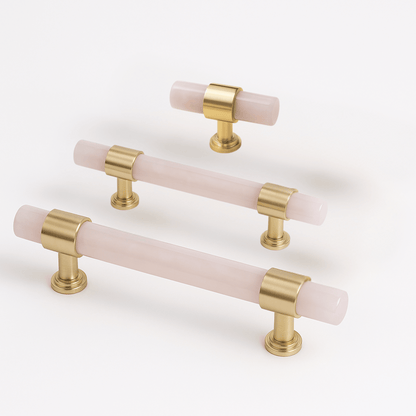 Set of gold and pink cabinet handles on a white background