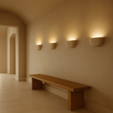 Wooden bench against a wall with three wall-mounted lights in a softly lit room.