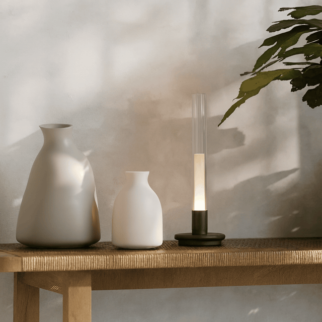 Two vases and a lamp on a wooden surface with a neutral background
