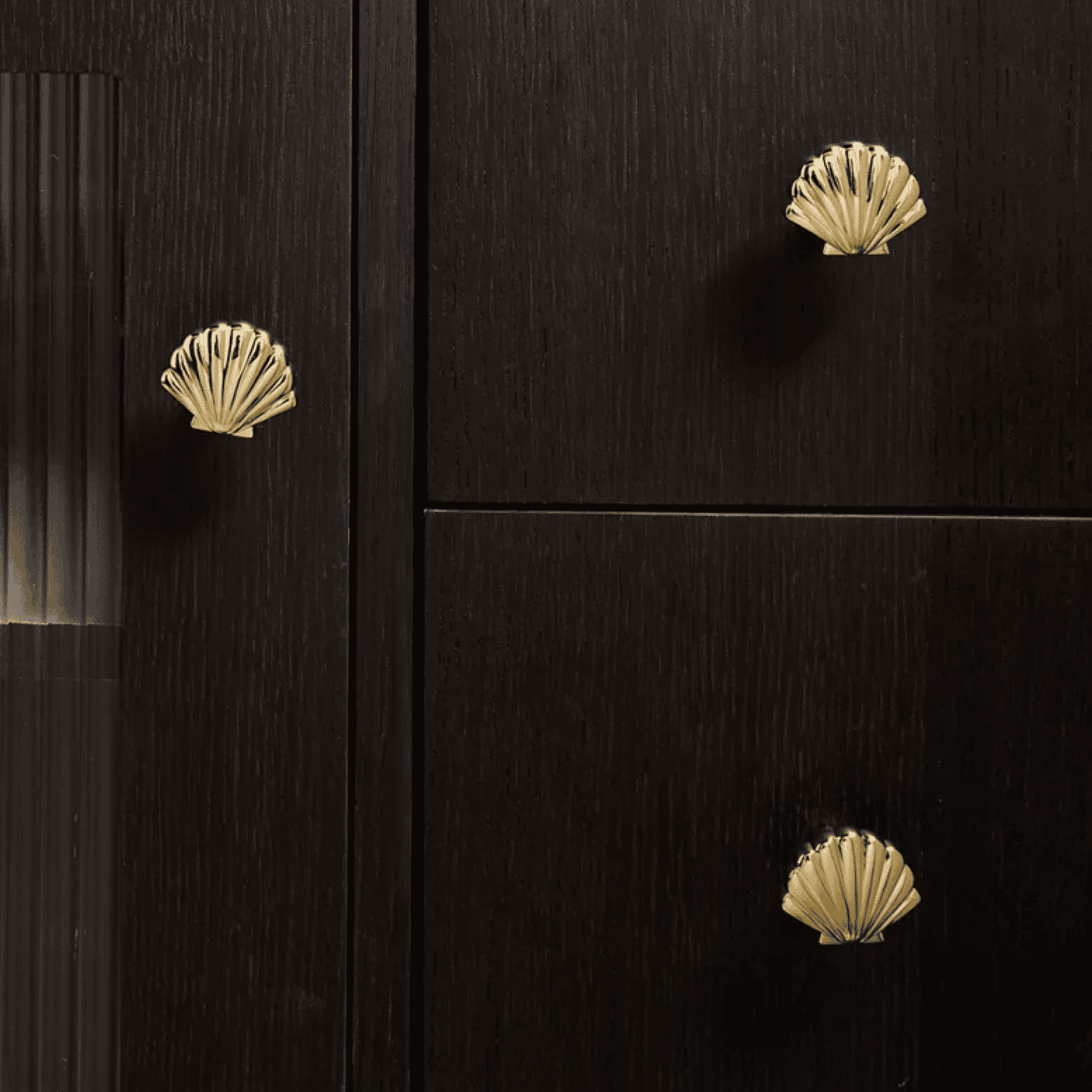 Black cabinet with gold shell-shaped knobs