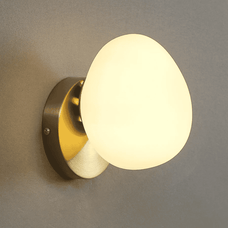 Wall-mounted light fixture with a round glass shade on a gray wall.