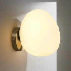Wall-mounted light fixture with a round glass shade on a gray wall