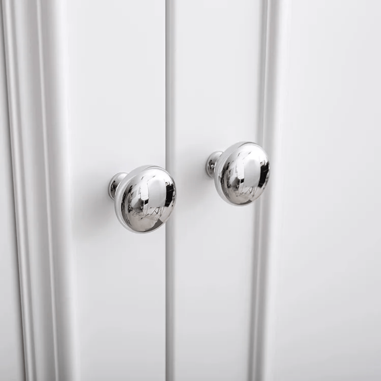 Close-up of a white cabinet with silver knobs on a white background