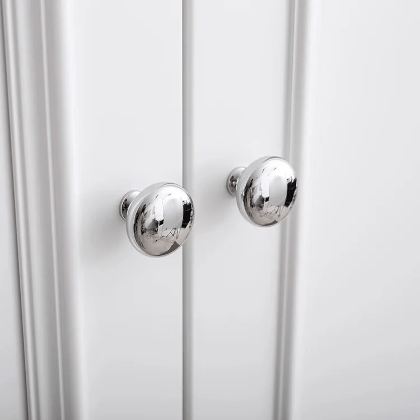 Close-up of a white cabinet with silver knobs on a white background