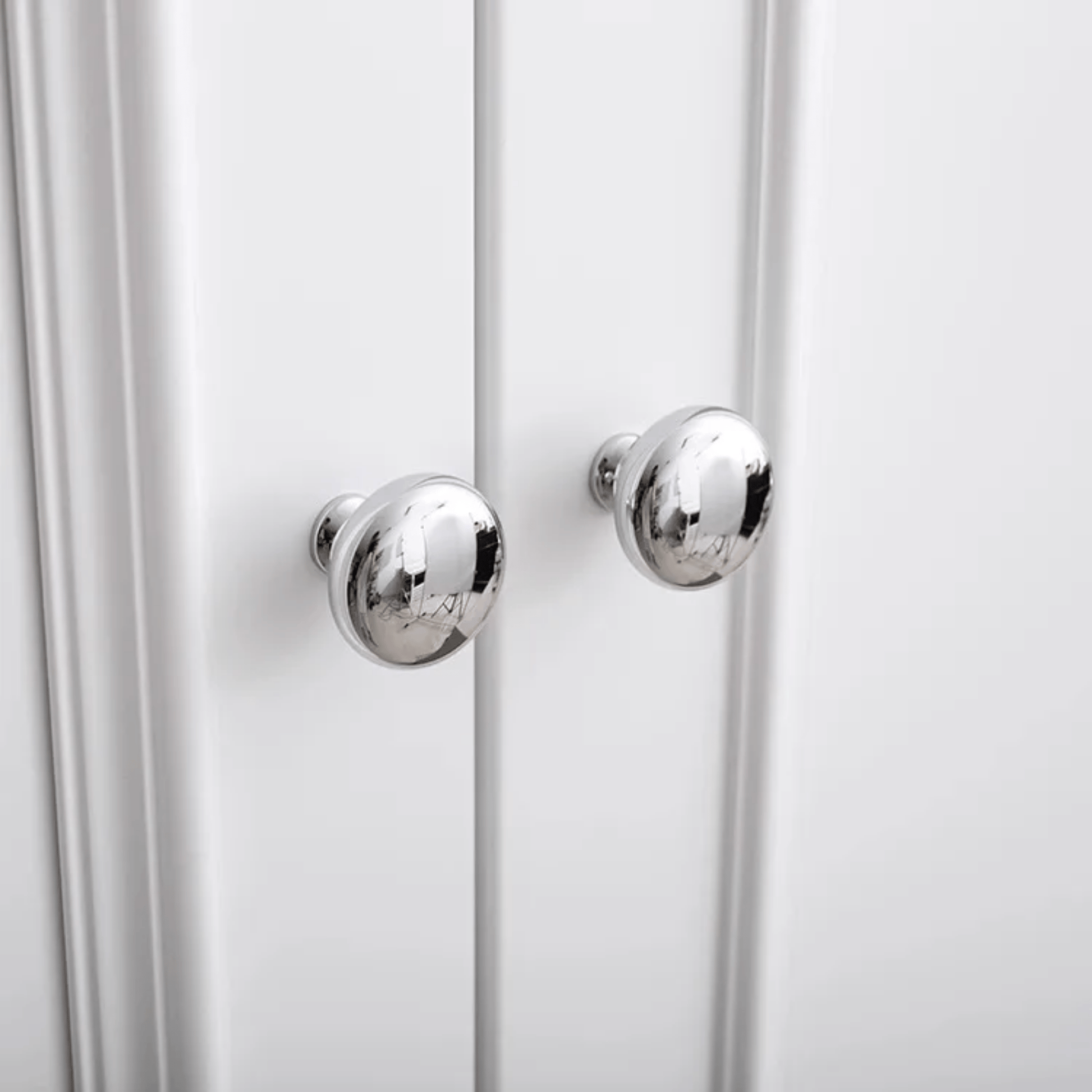 Close-up of a white cabinet with silver knobs on a white background
