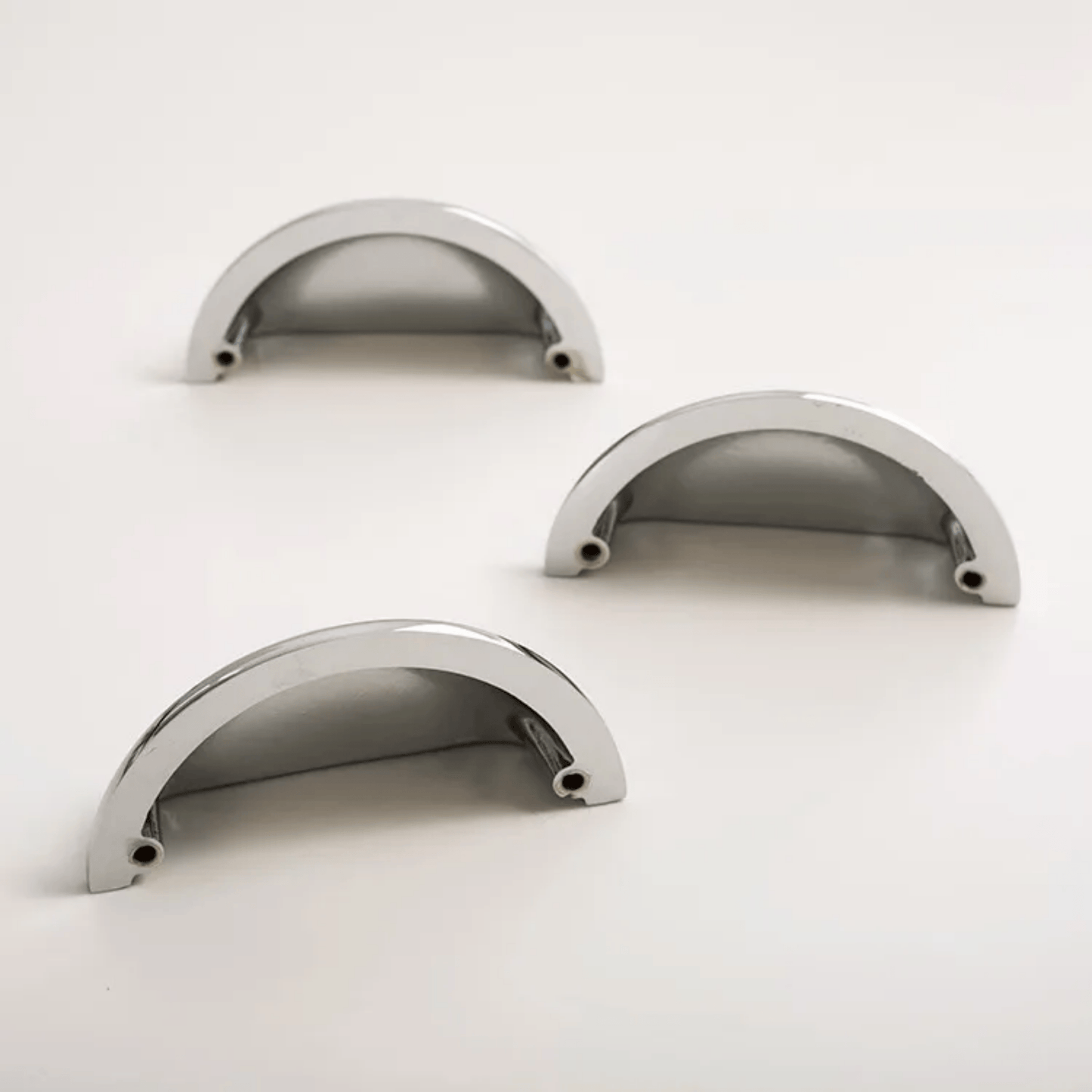 Three metallic curved objects on a white background