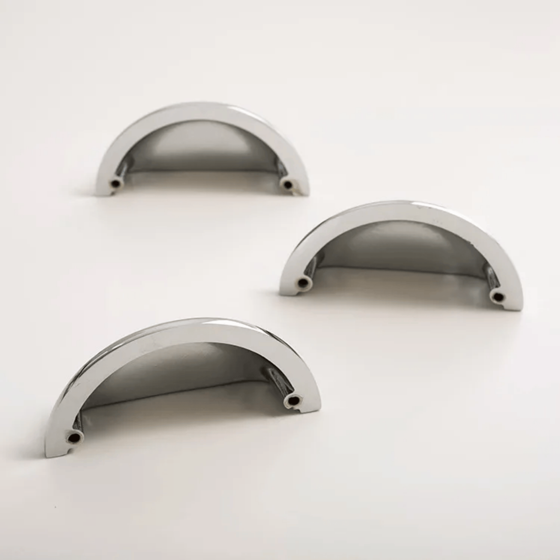 Three metallic curved objects on a white background