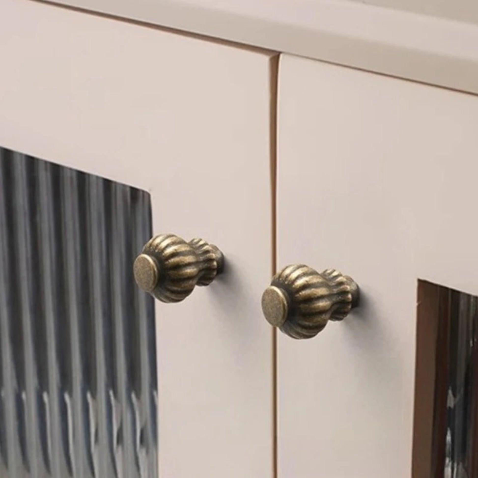 Close-up of a cabinet with decorative brass knobs on a light-colored wooden door.