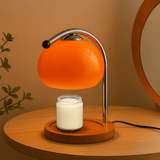 Table lamp with orange glass shade and wooden base on a wooden surface.