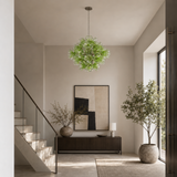 Modern interior with a chandelier, plants, and abstract art in a well-lit room.