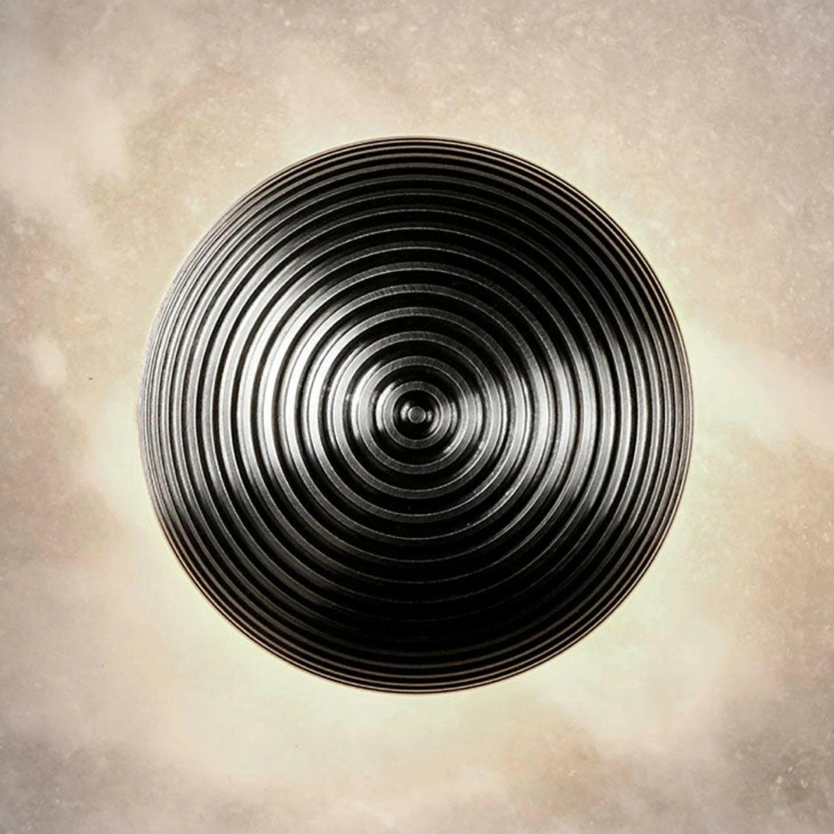 Black circular object with concentric rings on a textured beige background
