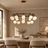 Marble ball light – 100cm Black – lifestyle Installed above dining table in elegant warm beige dining room, ceiling connection visible, exact scale relative normal furniture.