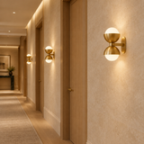 Gold brass glass wall lamps installed along a boutique hotel corridor