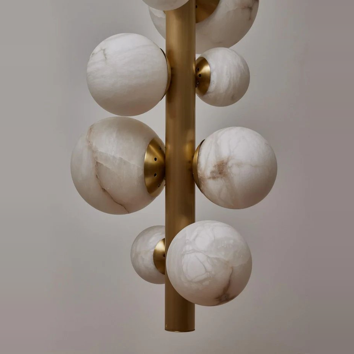 Decorative lamp with marble-like spherical elements on a gold fixture against a neutral background