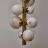 Decorative lamp with marble-like spherical elements on a gold fixture against a neutral background