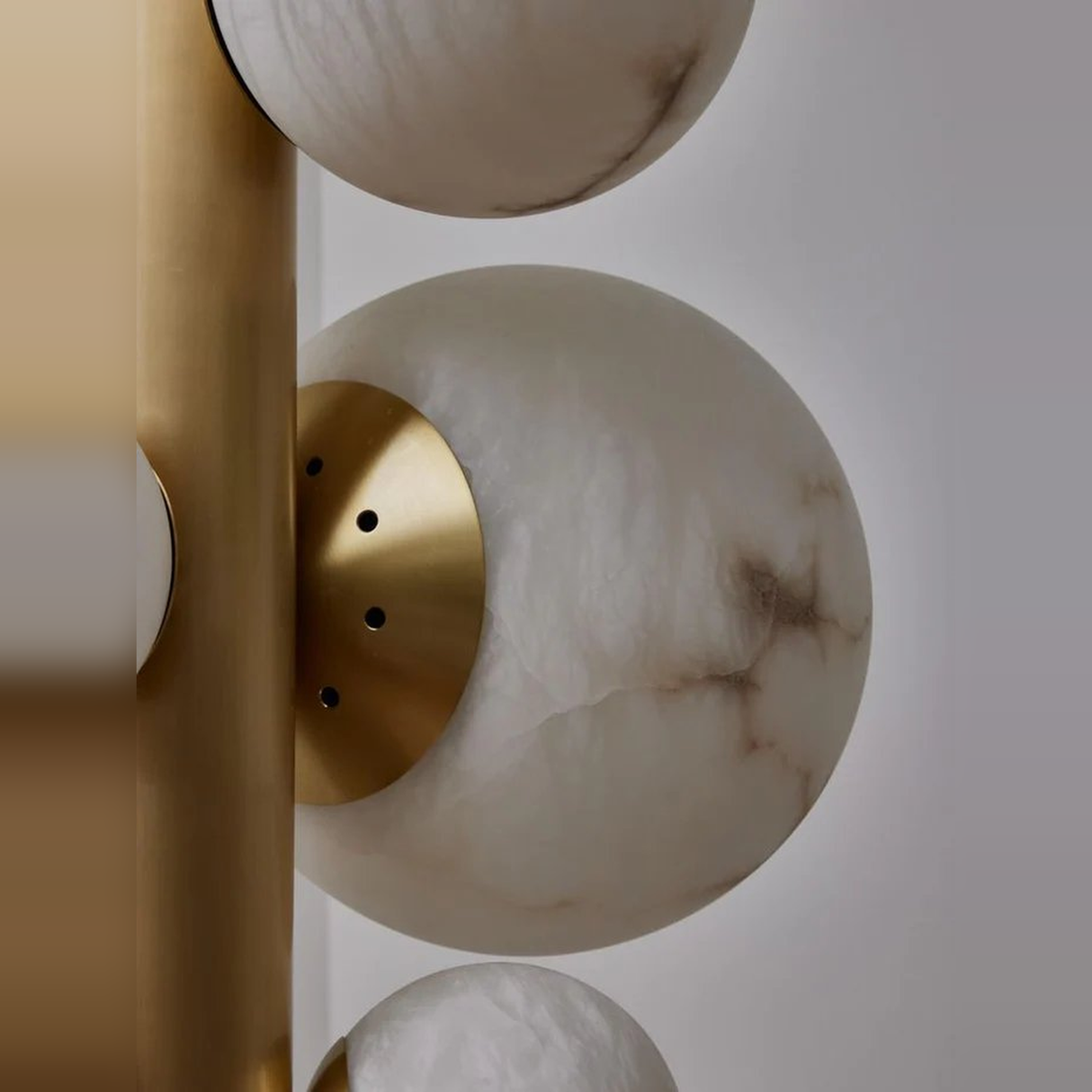 Decorative wall light fixture with marble-like spheres and gold accents on a neutral background