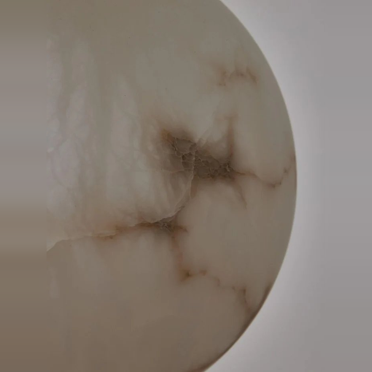 Close-up of a beige marble object with brownish veins on a light gray background