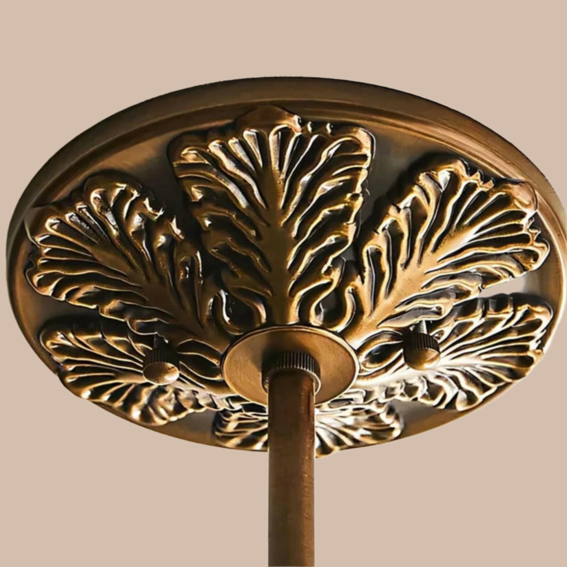 Close look at decorative bronze ceiling medallion with leaf pattern on a white background