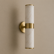 A modern cylindrical wall sconce with a white marble-look glass shade and brushed gold metal accents, mounted on a warm beige wall.