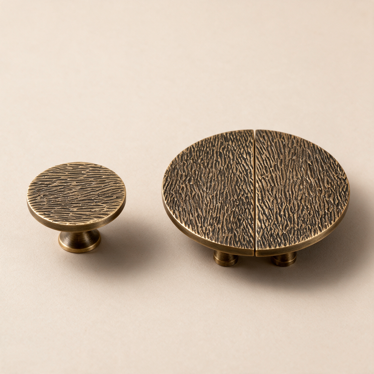 Two round cabinet knobs in an antique brass finish with a textured, wood-grain-like surface, displayed on a warm beige background.