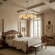 A luxury bedroom featuring a dark wood four-poster bed with beige linens, a matching wooden bench at the foot of the bed, a modern multi-light chandelier, and a cozy desk setup by a window.