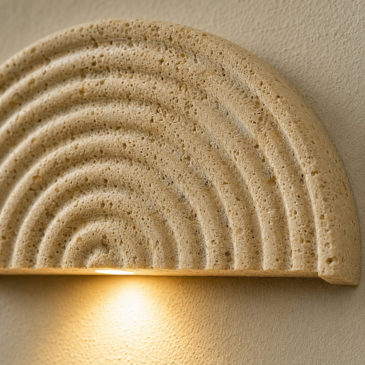 Close-up of the Kaeva wall sconce carved yellow-stone texture and warm light