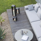 Outdoor patio with gray sofa, small table, and candle holders on a wooden deck.