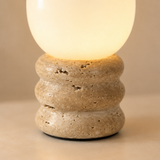 Close-up of frosted glass shade and porous yellow travertine ridged base