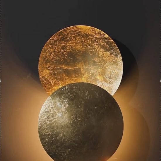Hand adjusting rotatable Moon Eclipse LED Wall Light. Creative lighting fixture with bronze alloy discs for customizable ambiance.