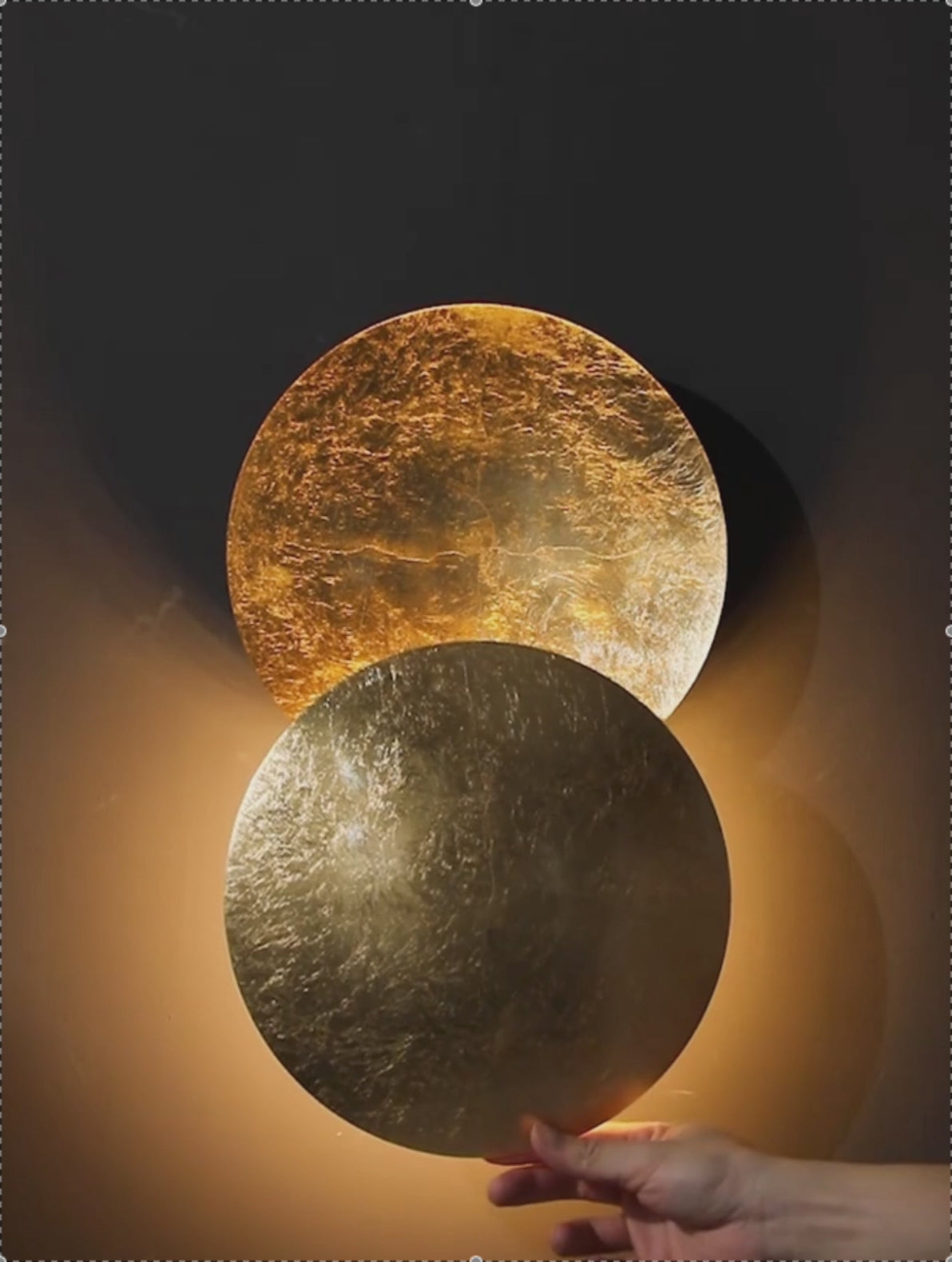 Hand adjusting rotatable Moon Eclipse LED Wall Light. Creative lighting fixture with bronze alloy discs for customizable ambiance.