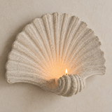 Close-up of the shell-shaped wall candle holder with a lit candle