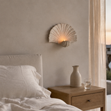 Shell-shaped wall candle holder in a serene boutique hotel bedroom
