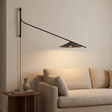 Soren Reach adjustable black LED wall lamp above a beige sofa