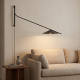 Soren Reach adjustable black LED wall lamp above a beige sofa